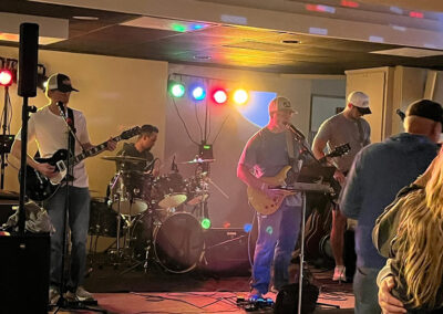 Live music is on stage with colorful lights at a dimly lit room.